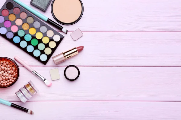 Diferentes cosméticos de maquillaje en mesa de madera rosa — Foto de Stock