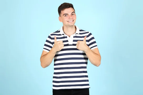 Joven mostrando pulgares arriba sobre fondo azul —  Fotos de Stock