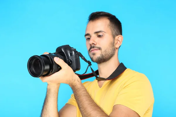 Joven fotógrafo con cámara sobre fondo azul —  Fotos de Stock