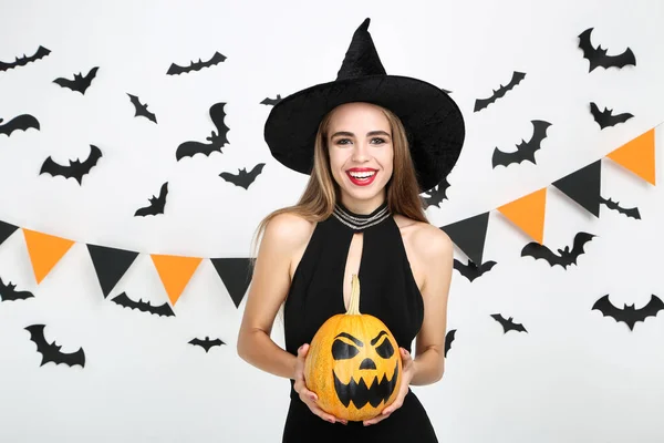 Mulher bonita em traje preto segurando abóbora halloween com — Fotografia de Stock