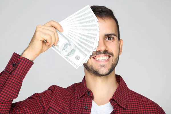 Joven hombre feliz sosteniendo billetes de dólar sobre fondo gris — Foto de Stock