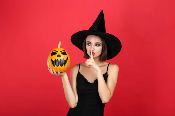 Happy young woman in black halloween costume holding pumpkin on — Stock Photo, Image