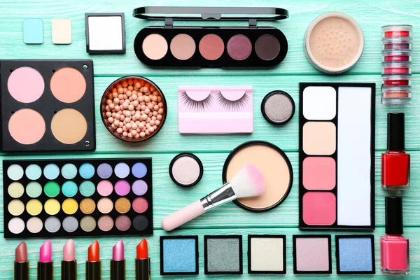 Different makeup cosmetics on mint wooden table