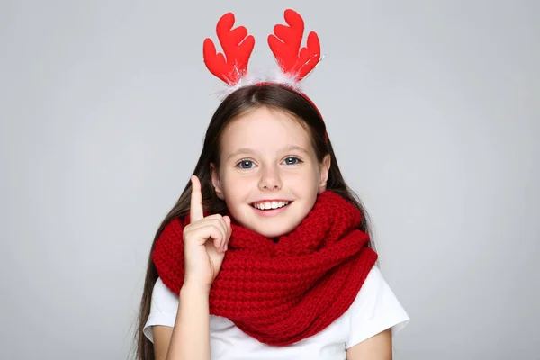 Petite fille en cornes rouges de Noël et foulard tricoté sur fond gris — Photo