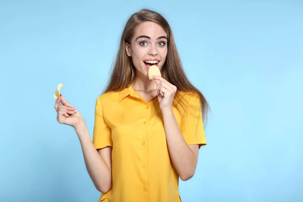 Junges schönes Mädchen mit Kartoffelchips auf blauem Hintergrund — Stockfoto