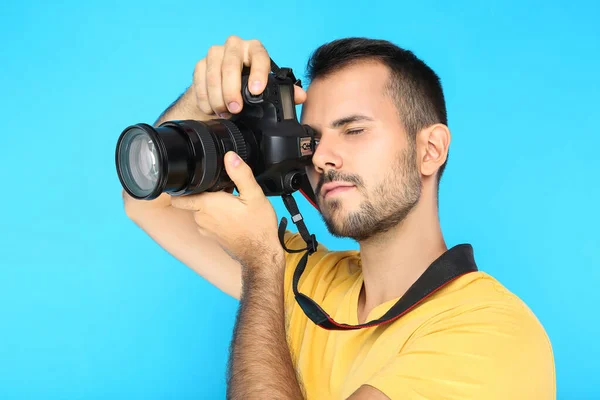 Joven fotógrafo con cámara sobre fondo azul —  Fotos de Stock