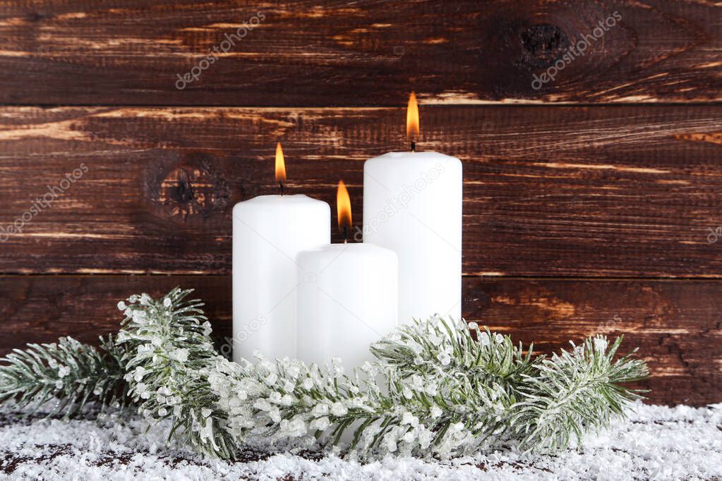 Christmas candles with fir tree branches on brown wooden backgro