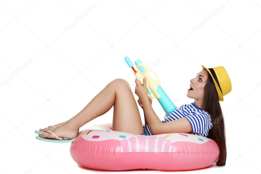 Young girl with water gun sitting on inflatable donut