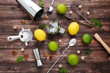 Kahverengi ahşap masada limonlu, limonlu ve şekerli barmen malzemeleri.