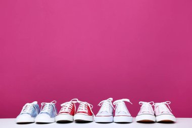 Pembe arka planda farklı renkli spor ayakkabılar.