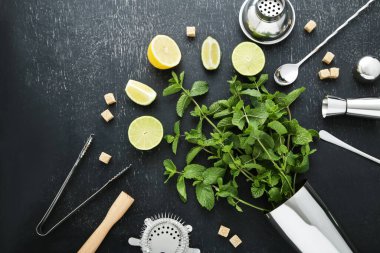 Barmen ekipmanları limonlu, limonlu ve siyah ahşap masada nane yapraklı.