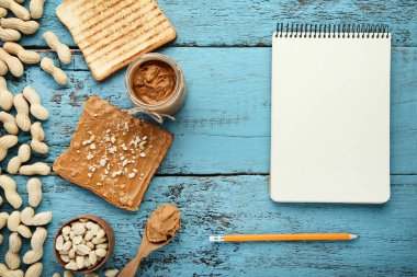 Fıstık ezmeli ekmek, fındık ve ahşap masada boş bir kağıt.