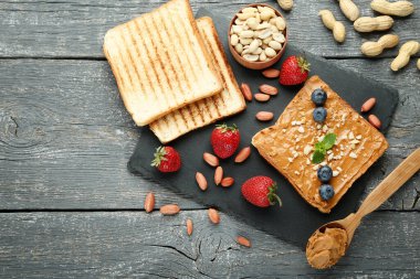 Fıstık ezmeli ekmek, ahşap masada meyve ve fındık.