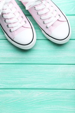 Naneli ahşap masada bir çift pembe spor ayakkabı.