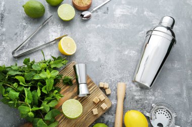 Gri ahşap masada limonlu, limonlu ve nane yapraklı barmen ekipmanları.