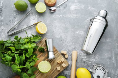 Barman equipments with limes, lemons and mint leafs on grey wooden table clipart