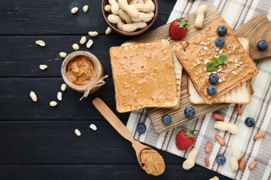 Fıstık ezmeli ekmek, siyah ahşap masada meyve ve fındık.