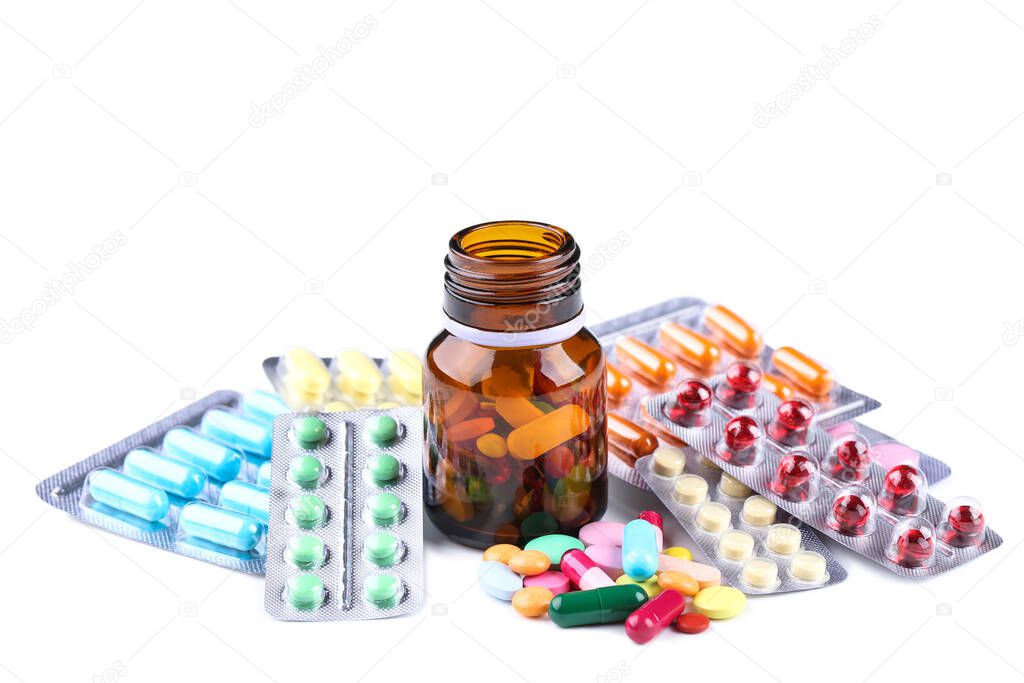 Colorful pills in blisters and bottle on white background