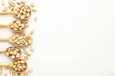 Beyaz ahşap masadaki kaşıklarda fıstıklar