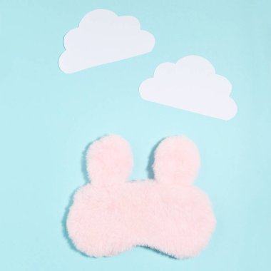 Mavi arka planda kağıt bulutlar olan uyku maskesi. Minimalizm kavramı