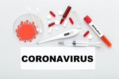 Coronavirus 'a hapları, termometreyi, test tüpünü, şırıngayı ve gri arka plandaki ampulü yaz.