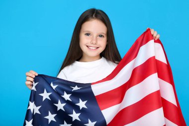 Mavi arka planda Amerikan bayrağı tutan genç kız