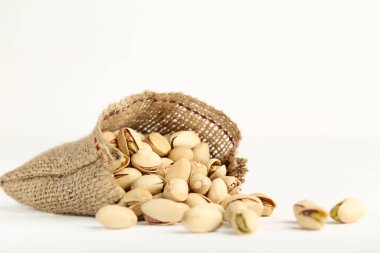 Beyaz arka planda çuval içinde lezzetli fıstıklar
