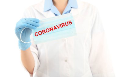 Coronavirus metniyle doktor maskesini tutuyor.