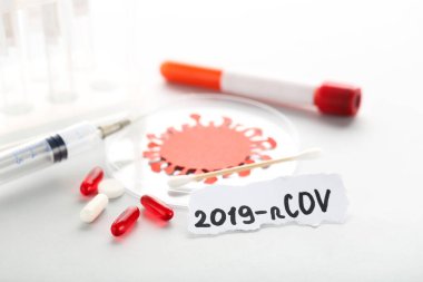 Metin 2019-nCov haplar, test tüpü ve gri arka planda şırınga