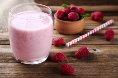 Kahverengi ahşap masada, camlı ahududu smoothie.