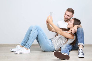 Mutlu genç çift akıllı telefondan selfie çekiyor.