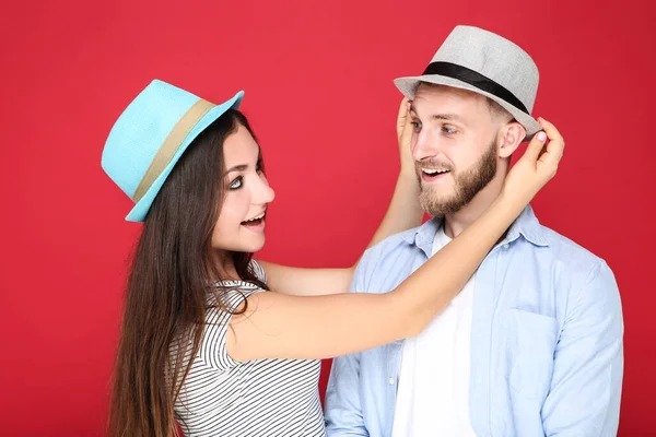 Happy young couple in hats on red background