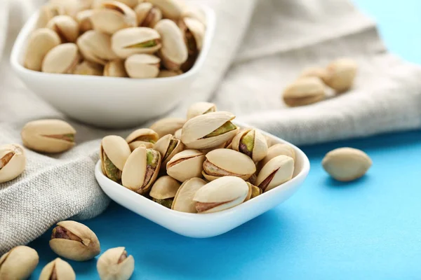 Sabrosos Pistachos Cuencos Con Servilleta Sobre Fondo Azul —  Fotos de Stock