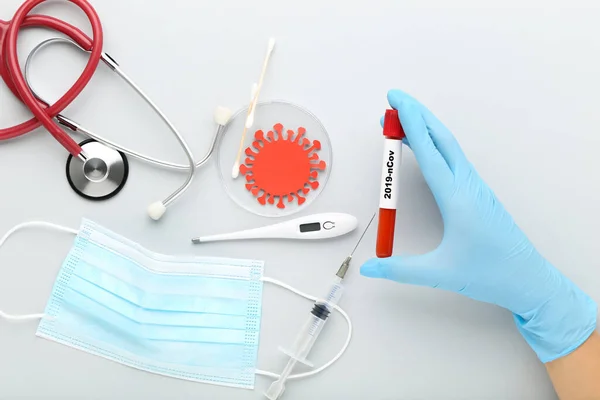 Medicine mask with stethoscope, thermometer, syringe and text tube with blood on grey background