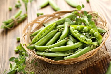 Kahverengi ahşap masada yeşil bezelye kabukları.