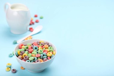 Mavi arka planda kavanozda süt olan renkli mısır halkaları