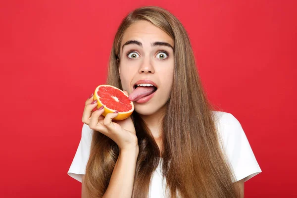 Junges Mädchen Isst Frische Grapefruit Auf Rotem Hintergrund — Stockfoto