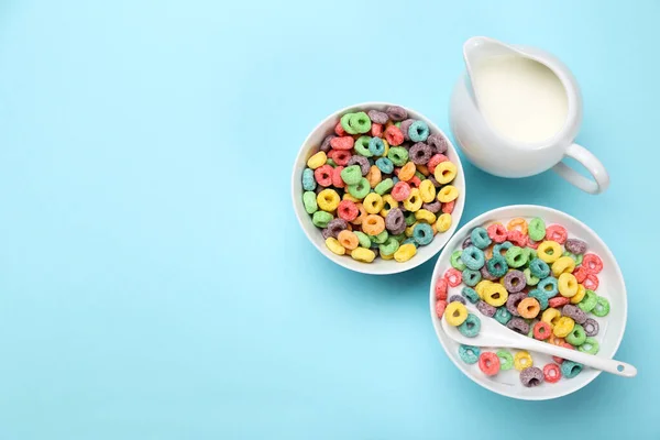 色彩斑斓的玉米圈 碗里有牛奶和勺子 背景是蓝色的 — 图库照片