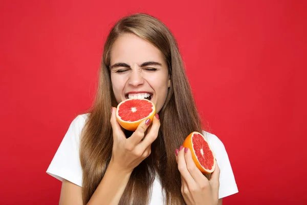Mladá Dívka Jíst Čerstvé Grapefruit Červeném Pozadí — Stock fotografie