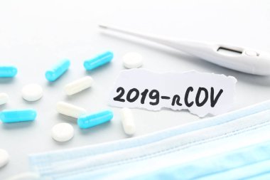 Metin 2019-nCov haplar, ilaç maskesi ve gri arka planda termometre