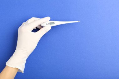 Doktor termometreyi mavi arkaplanda tutuyor