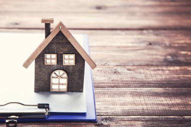 Kahverengi ahşap masada panosu olan ev modeli.