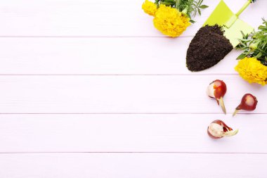 Pembe ahşap masada çiçekli bahçe küreği