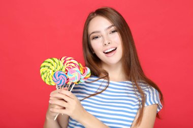 Kırmızı arka planda renkli lolipopları olan güzel bir kız.