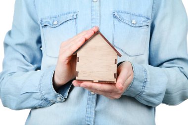 Ahşap ev modelini tutan kadın eller.