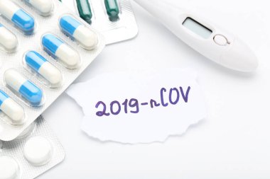 Metin 2019-nCov beyaz arka planda haplar ve termometreyle