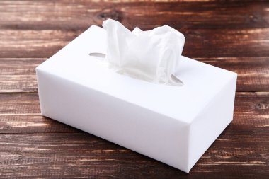 Kahverengi ahşap masada kağıt peçete kutusu.