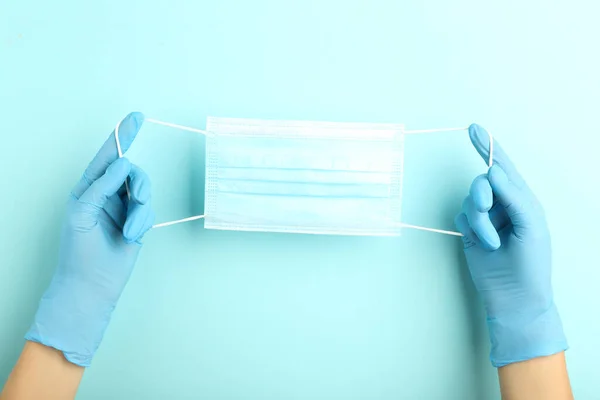 Medicine face mask and female hands in gloves on blue background