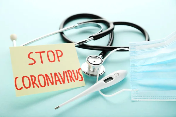 Text Stop Coronavirus with medicine mask, thermometer and stethoscope on blue background