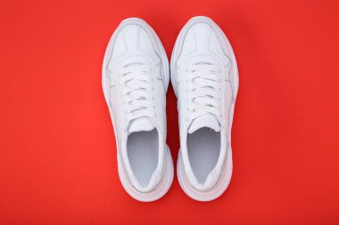 Kırmızı arkaplanda bir çift beyaz ayakkabı